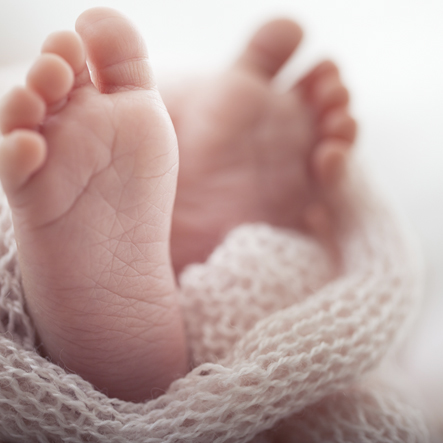 Lieve blote baby voetjes gewikkeld in een poederroze gebreide deken